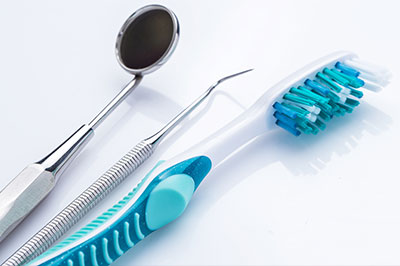 An image featuring a collection of dental tools including a toothbrush, dental mirror, and dental probe on a white background.