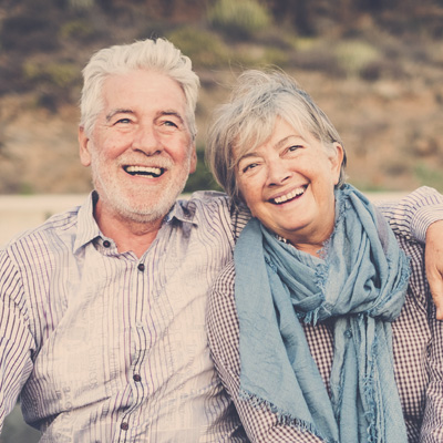 A woman with a radiant smile is leaning on a wooden chair, exuding confidence and joy.