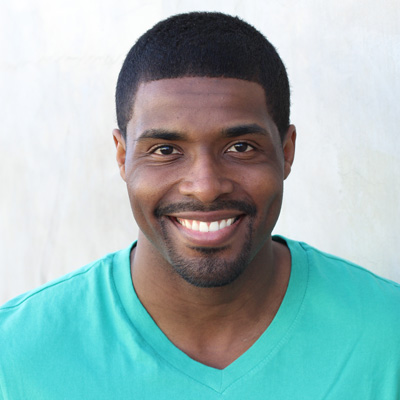 The image shows an older couple, a man and a woman, sharing a warm embrace. They are outdoors during the daytime, with clear skies and natural lighting. Both individuals are smiling and appear to be in a joyful mood.