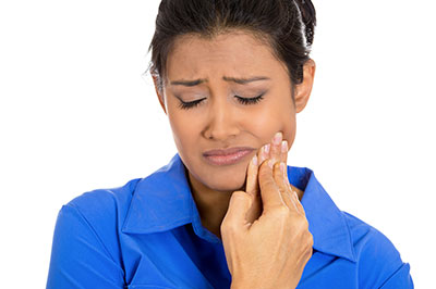 Woman with hand to face, looking down in apparent distress or concern.