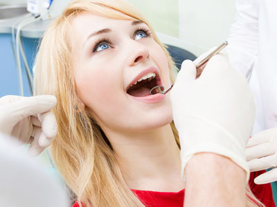 A woman in a dental chair receiving oral care, with a dental hygienist performing the procedure.